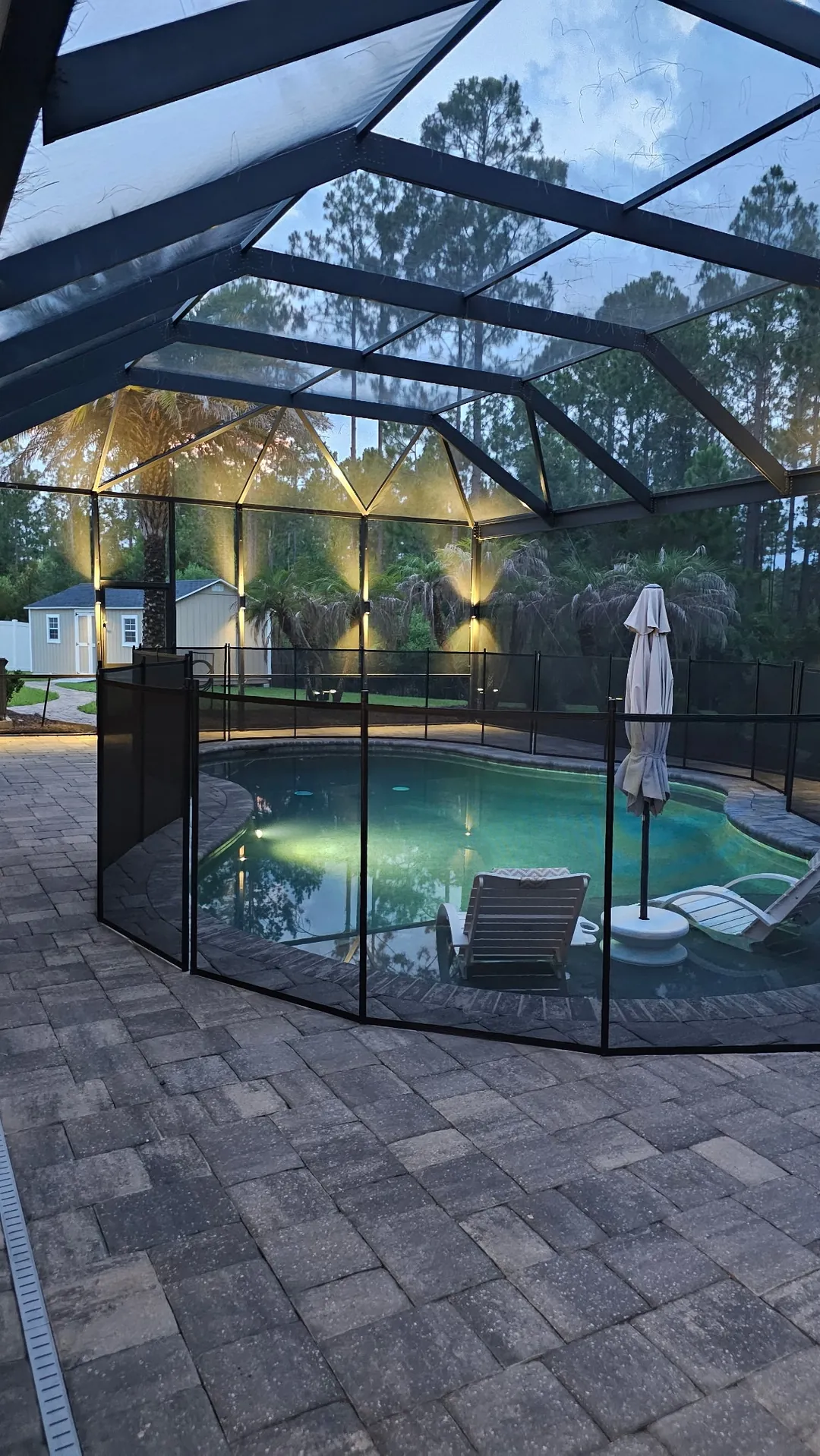 The enclosure at dusk, frame lights over the pool